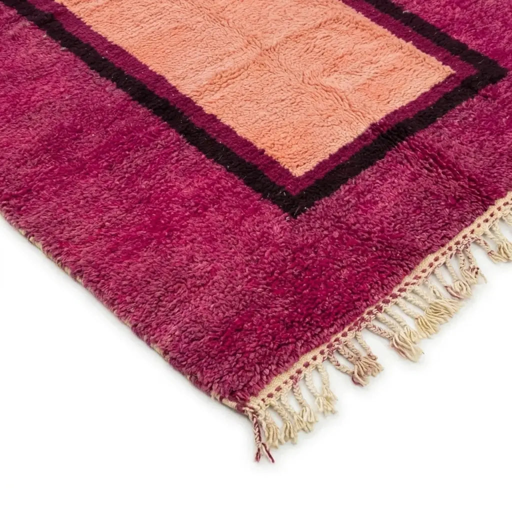 Détail des franges d’un tapis berbère rose fuchsia avec centre pêche, soulignant une finition artisanale haut de gamme et durable