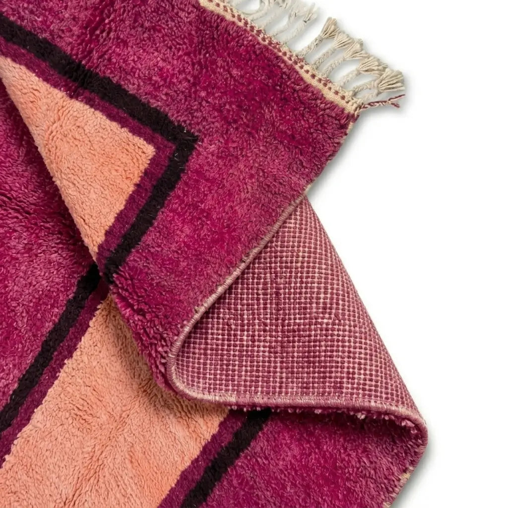 Détail du dessous antidérapant d’un tapis berbère rose fuchsia avec centre pêche, assurant stabilité et maintien optimal sur tous types de sols