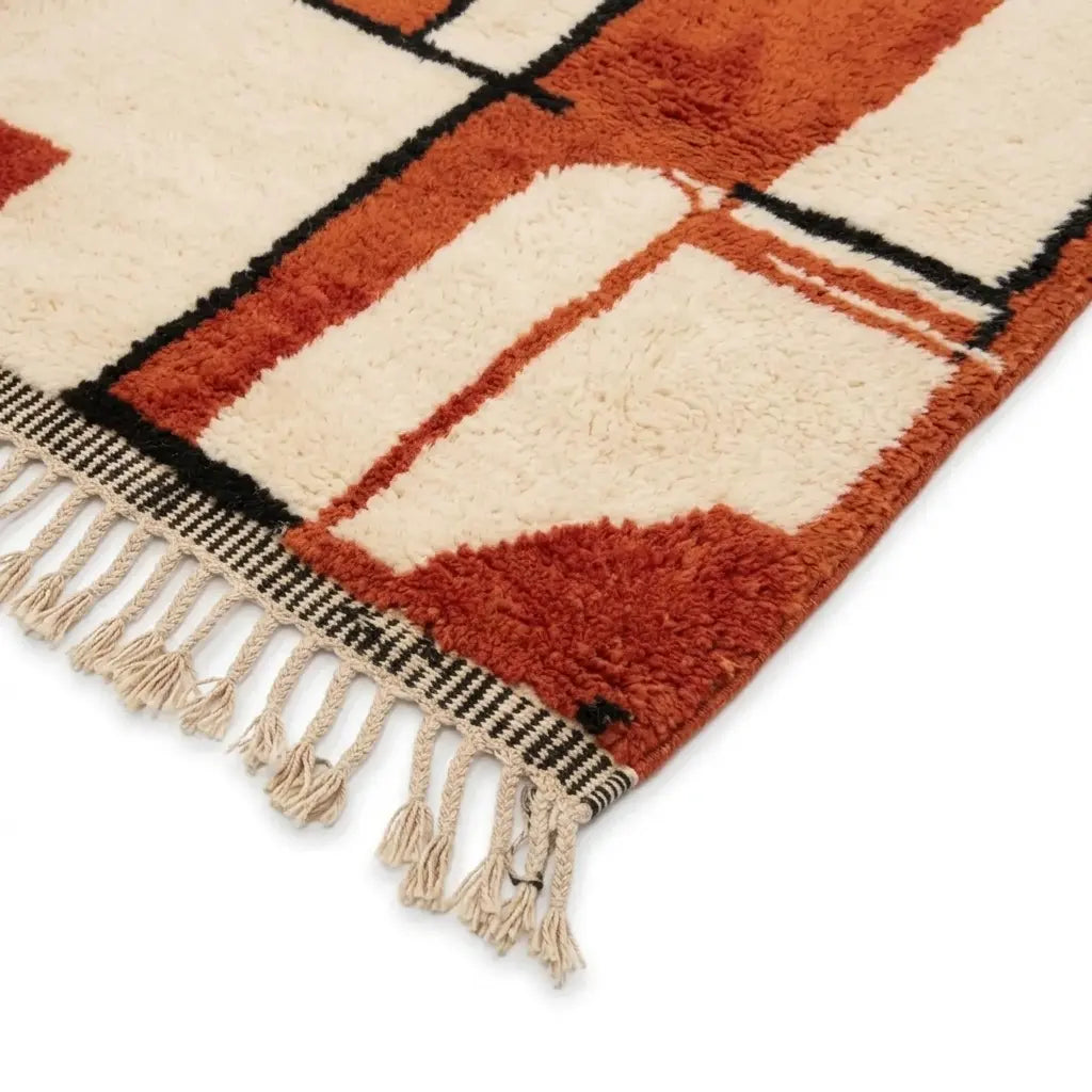 Détail tapis berbère rouge et crème avec franges blanches finition artisanale motifs géométriques modernes