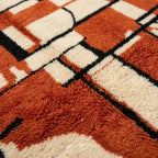 Gros plan tapis berbère rouge terracotta et crème avec motifs abstraits noirs design marocain contemporain
