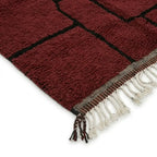 Détail des franges et finitions d’un tapis berbère rouge en laine, soulignant le savoir-faire artisanal et la qualité premium