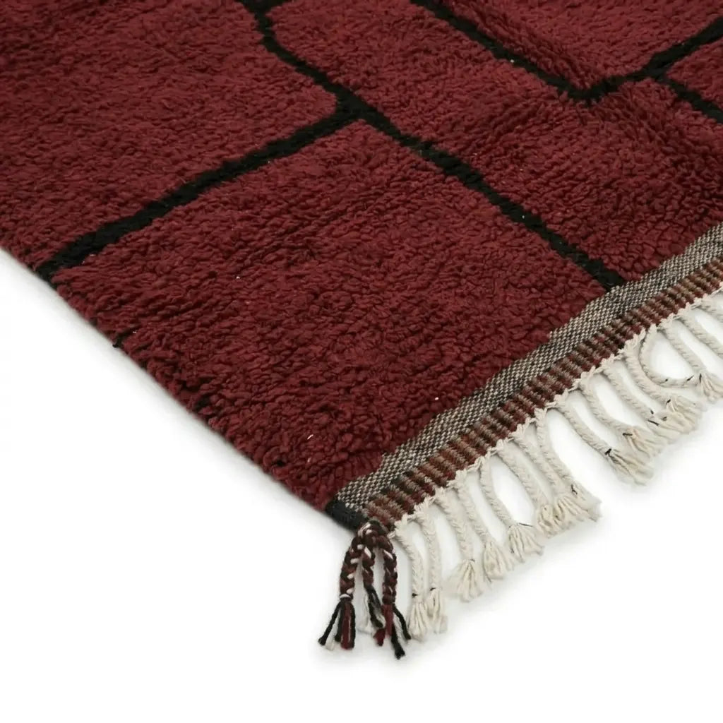 Détail des franges et finitions d’un tapis berbère rouge en laine, soulignant le savoir-faire artisanal et la qualité premium