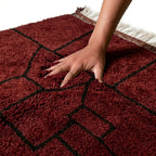 Tapis berbère en laine rouge avec motifs géométriques noirs, texture épaisse et douce pour un intérieur chaleureux et confortable