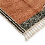coin de tapis berbère terracotta avec bordure noire et blanche graphique et franges écrues, design moderne et bohème