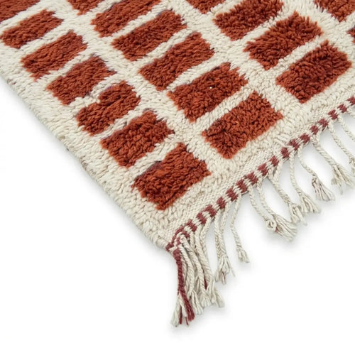 Détail tapis berbère terracotta à motifs carreaux avec franges finition artisanale marocaine haut de gamme
