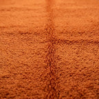 Gros plan tapis berbère terracotta avec relief central en laine épaisse design artisanal marocain authentique