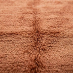 détail du relief central sur tapis berbère terracotta à poils longs, texture dense et finition artisanale premium