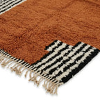 Détail tapis berbère terracotta avec franges et bordures noires et blanches finition artisanale marocaine