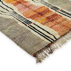 Détail tapis berbère terracotta avec franges et finitions artisanales motifs noirs et crème design marocain
