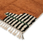 Détail tapis berbère terracotta avec franges et motifs rayés noirs et blancs finition artisanale marocaine