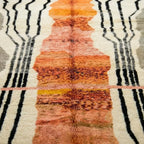 Gros plan tapis berbère terracotta avec motifs graphiques noirs et crème texture laine épaisse artisanat marocain