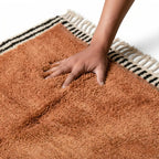 main pressant tapis berbère terracotta ultra doux avec bordure graphique noir et blanc et franges, confort moelleux haut de gamme