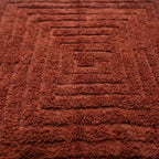 gros plan sur tapis berbère terracotta avec motif géométrique en relief, fibres denses et finition artisanale haut de gamme