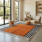 Tapis berbère terracotta avec bordures rayées noires et blanches dans salon lumineux style bohème moderne