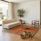 Tapis berbère terracotta avec bordures rayées noires et blanches dans salon bohème lumineux décoration chaleureuse