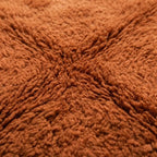 Gros plan tapis berbère terracotta en laine épaisse texture moelleuse artisanat marocain haut de gamme