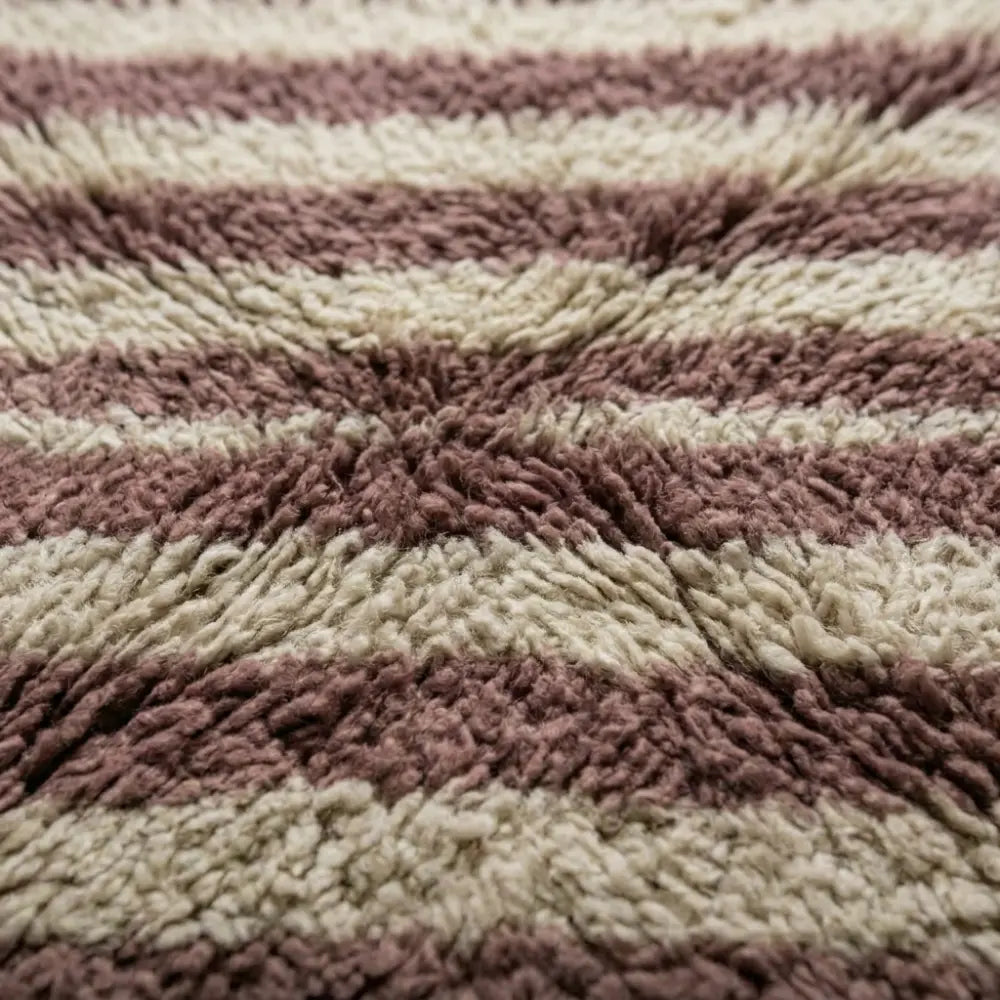 Détail texture tapis berbère fait main avec fibres épaisses et rayures rose et écru, qualité artisanale premium
