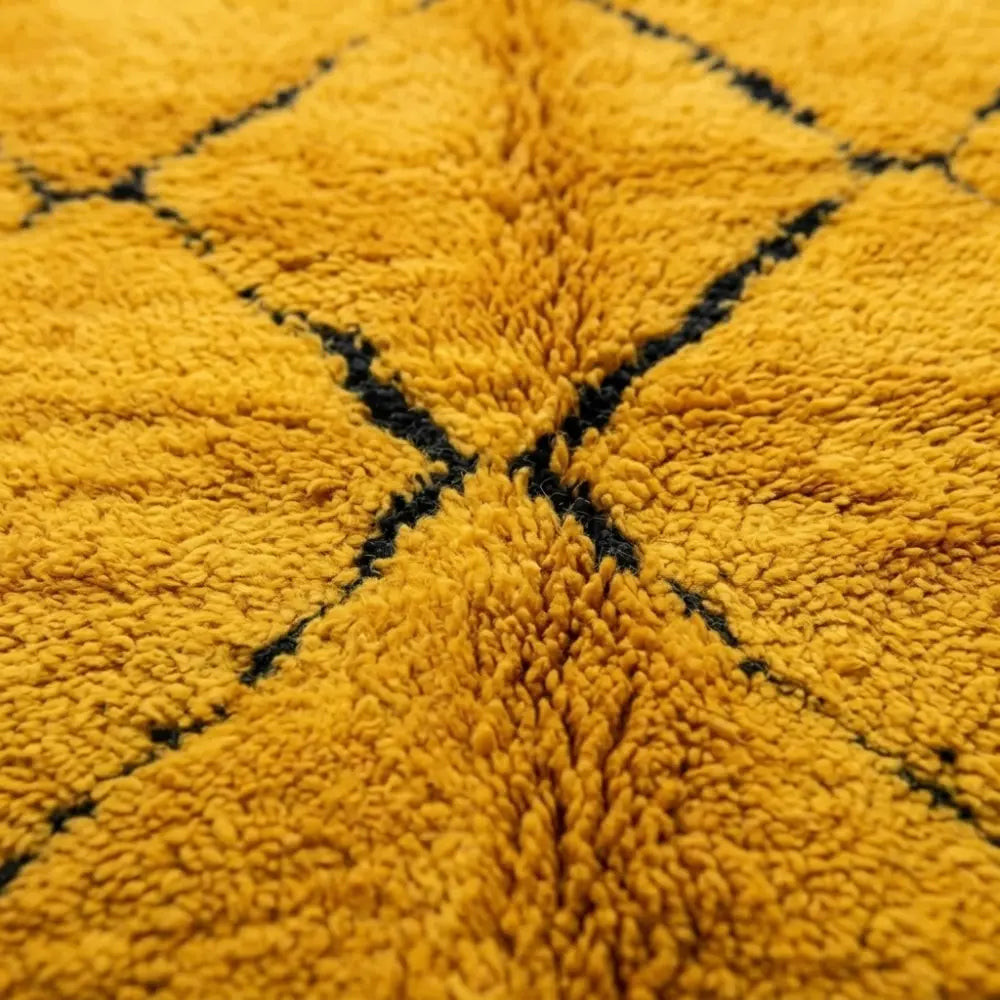 Gros plan texture tapis berbère en laine épaisse jaune avec motifs géométriques noirs artisanat marocain