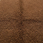 gros plan sur texture tapis berbère marron en laine épaisse, finition artisanale et fibres naturelles pour intérieur cosy