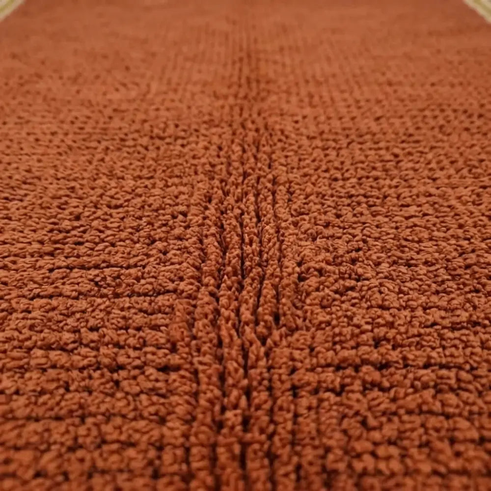 Gros plan sur texture tapis berbère ocre en laine, finition artisanale et confort doux premium