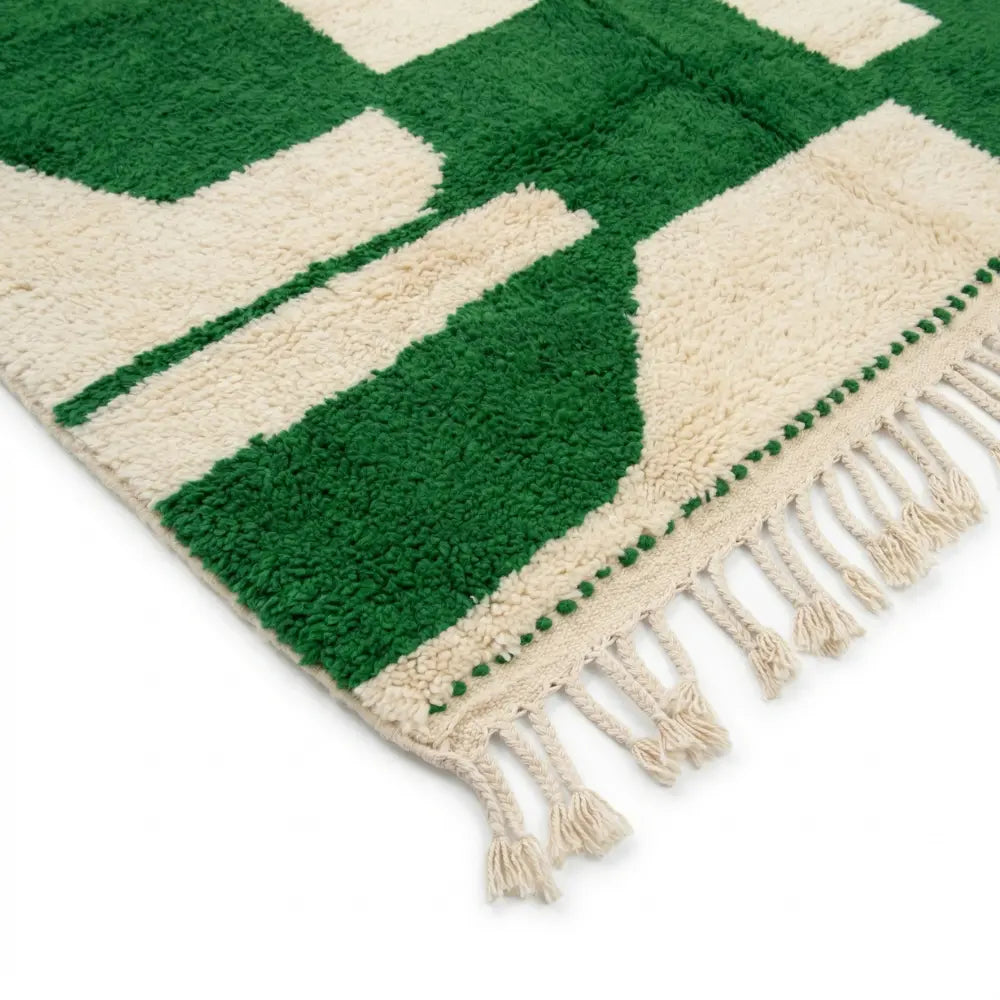 Détail des franges et finitions artisanales d’un tapis berbère vert et blanc