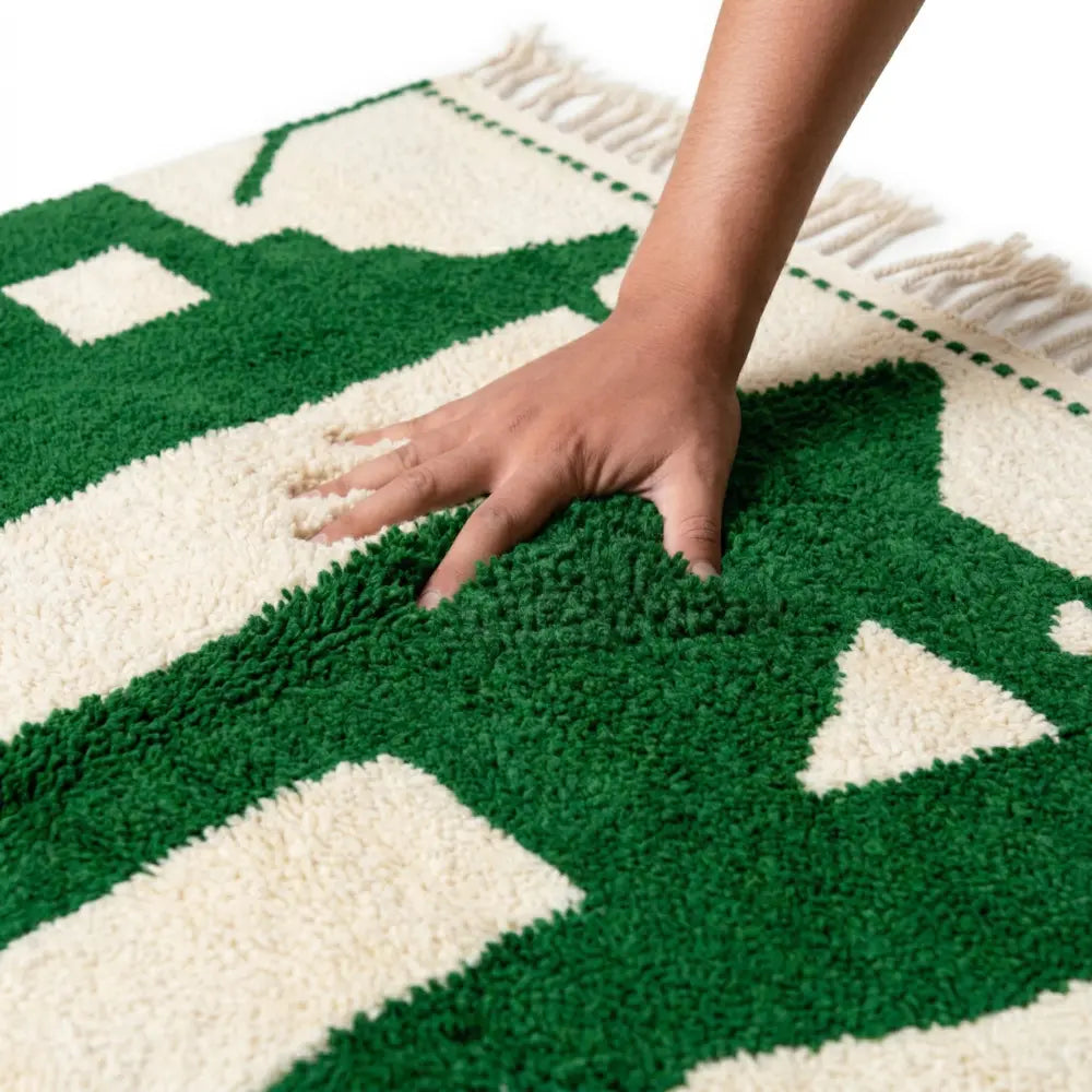 Main appuyant sur tapis berbère vert et blanc montrant une texture douce et moelleuse