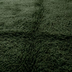 gros plan sur texture dense du tapis berbère vert foncé, fibres épaisses et finition haut de gamme pour intérieur cosy