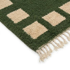 coin de tapis berbère vert avec carrés beiges et franges tressées, design artisanal idéal pour décoration moderne