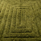 détail tapis berbère vert olive avec motif géométrique en relief, texture moelleuse et finition artisanale haut de gamme