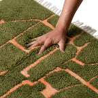 main enfoncée dans tapis berbère vert et terracotta ultra doux à poils longs, mettant en avant confort supérieur et qualité haut de gamme